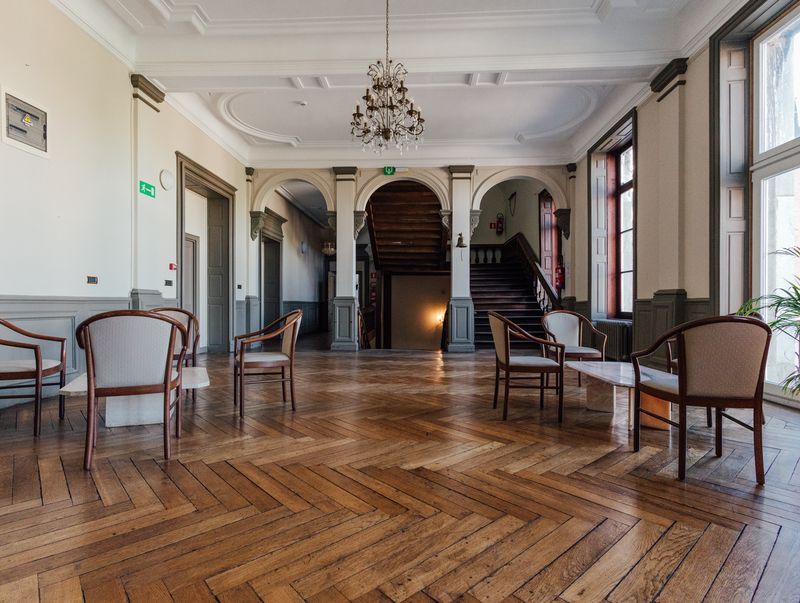 Grand salon parqueté sous un lustre en cristal – Château de la Neuville