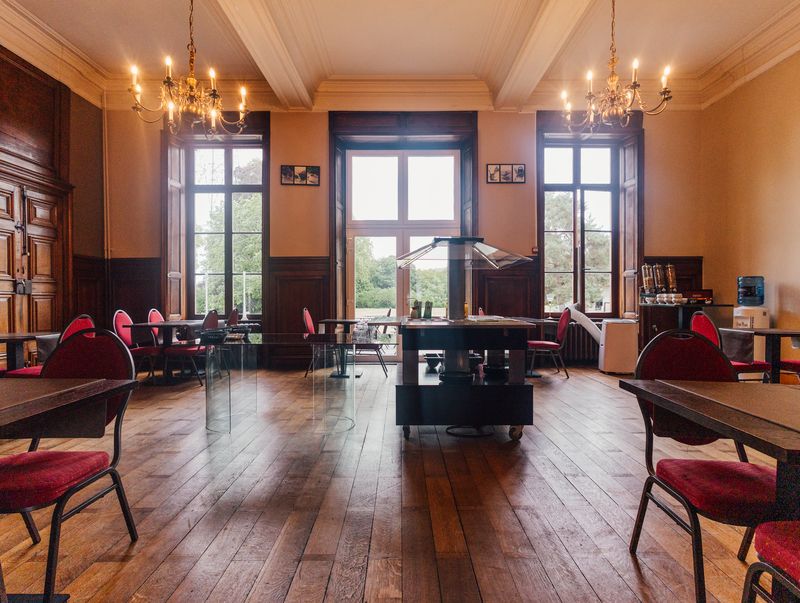 Salle aux lustres et boiseries sombres – Château de la Neuville